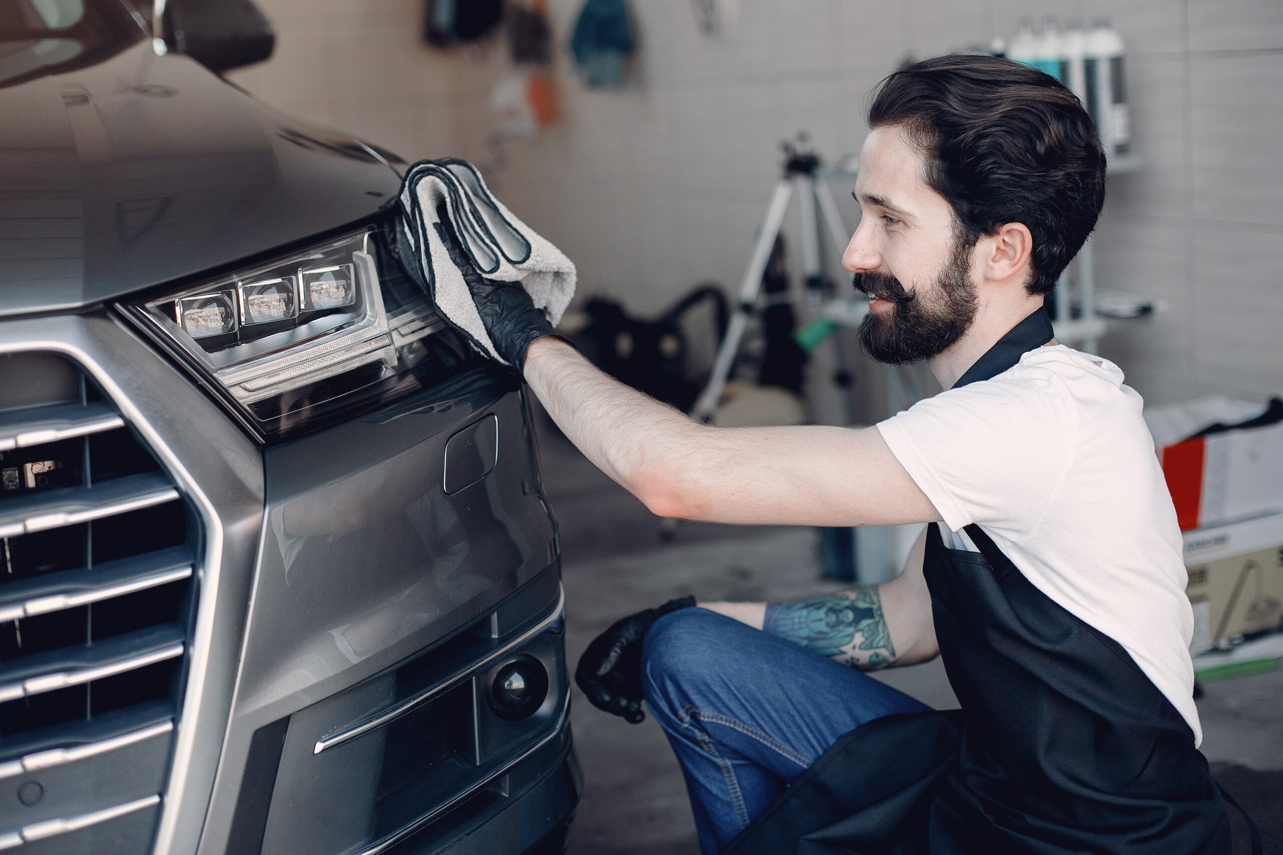 Man in a garage. Worker polish a car.